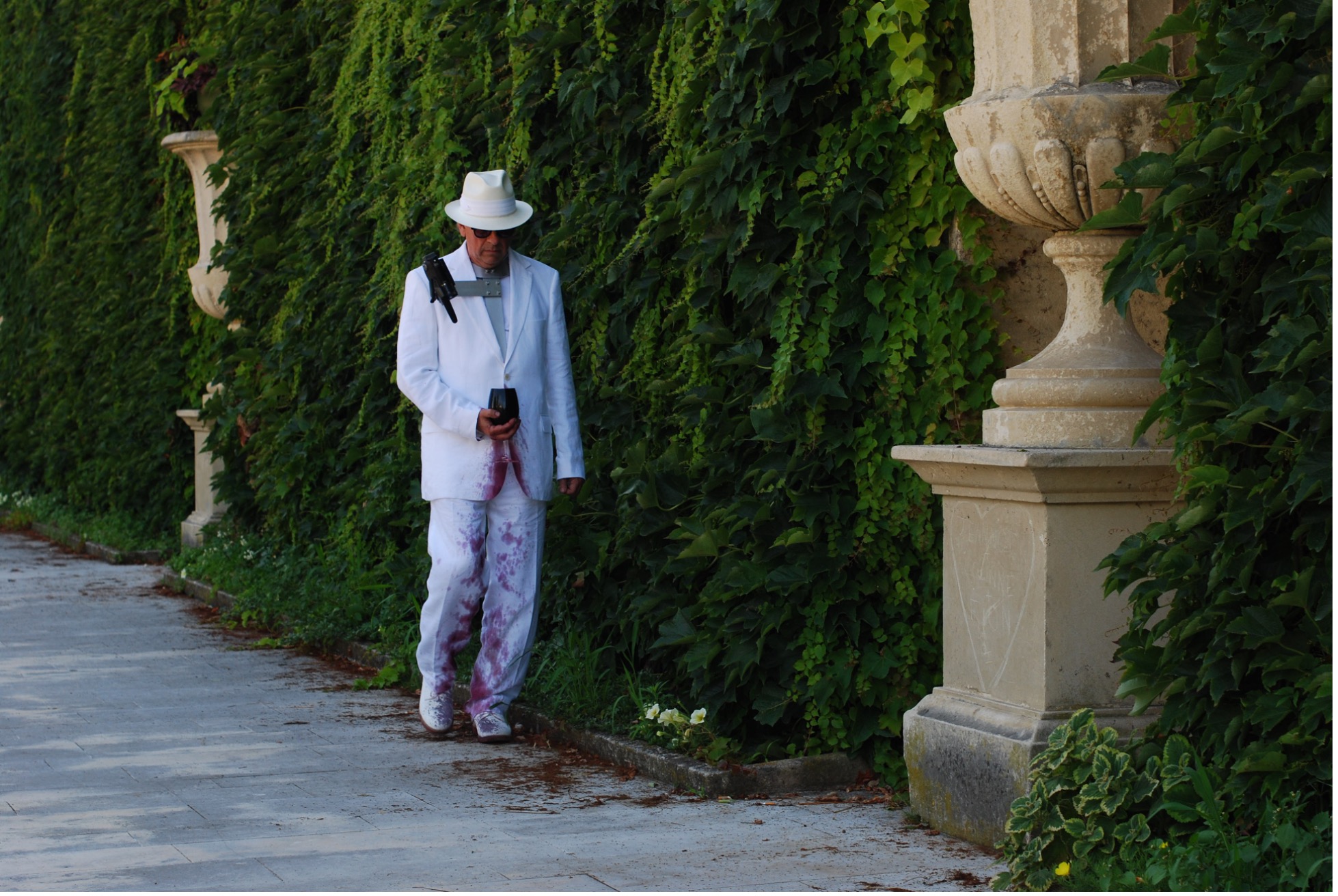 A person in white suit and hat walking on sidewalk