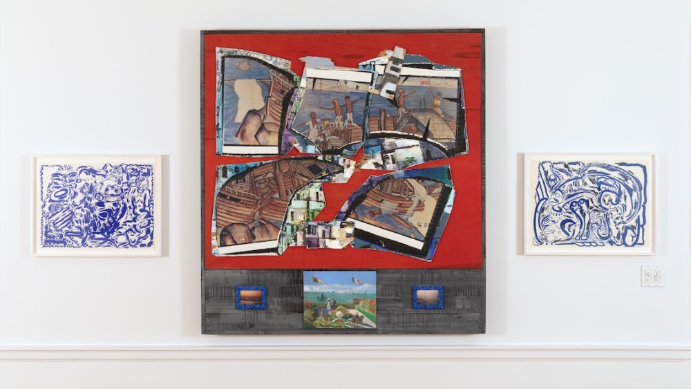 Installation image of three works, two smaller blue prints on each side of a larger mixed media work