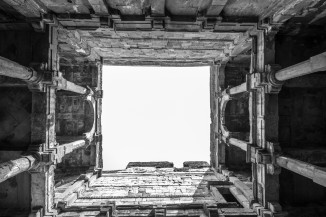 A view of the open sky, framed by pillared galleries and parallel walls, taken from the depths of Jethabhai vaav.