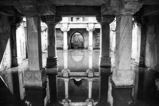 The pillared galleries of Jethabhai vaav casting reflections in still water.